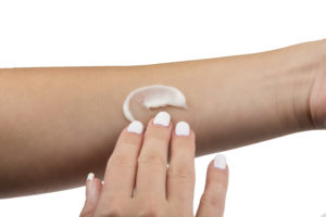 Woman applying LMX4 topical cream to forearm